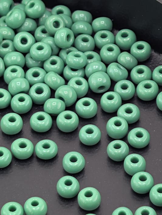 a collection of green glass beads scattered on a dark surface.