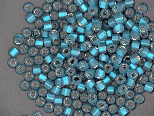a large pile of blue and silver beads scattered on a gray surface.