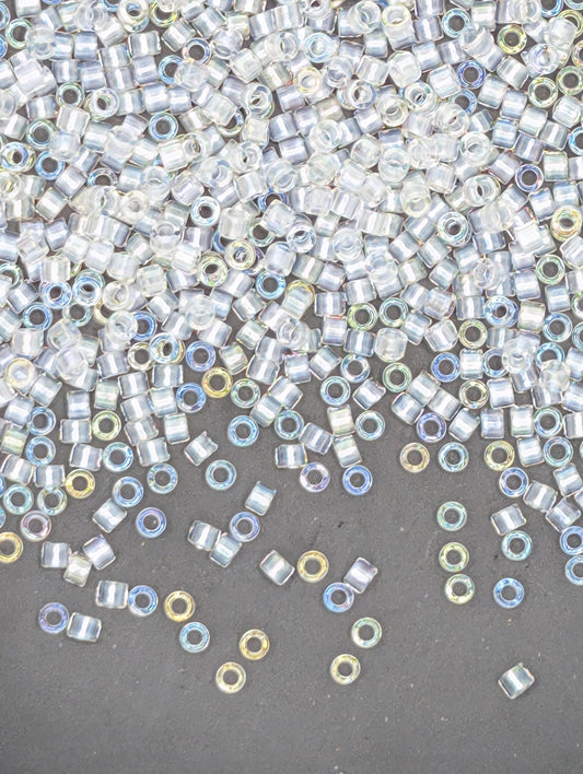 The image is a collection of numerous small, clear beads scattered across a dark surface.