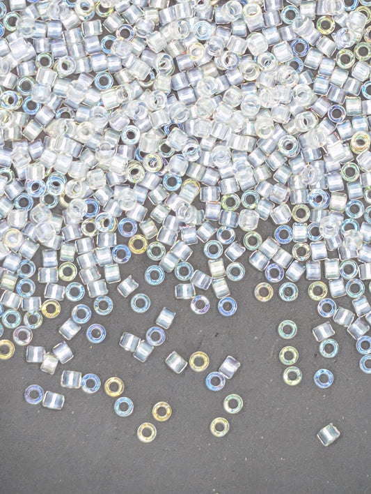 The image is a collection of numerous small, clear beads scattered across a dark surface.