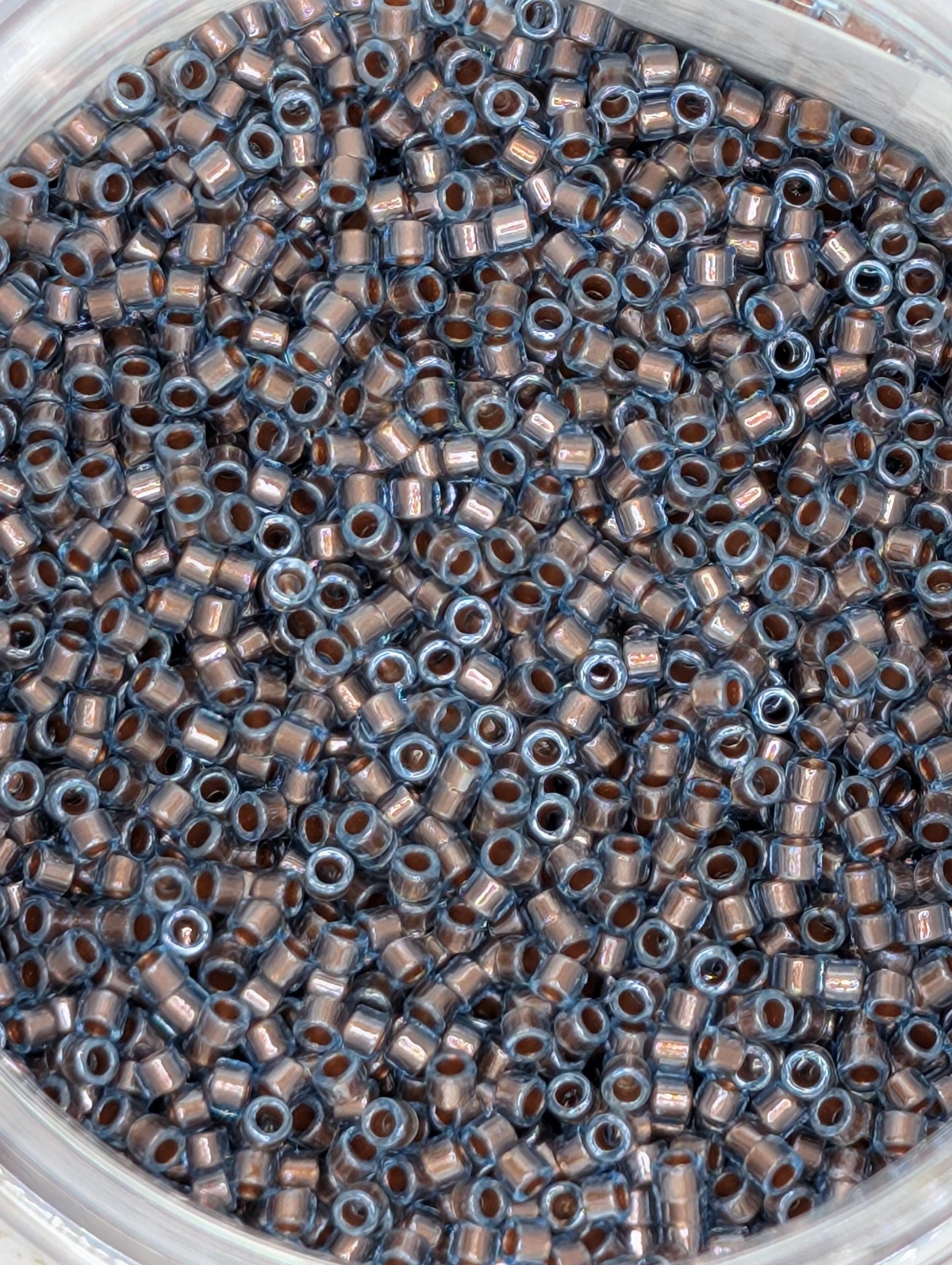 A close-up image of a container filled with numerous small, circular beads in various shades of blue and brown.