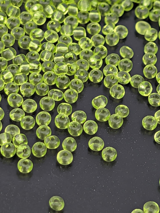 a collection of small, clear, neon green beads scattered on a dark surface.