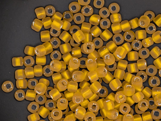a collection of yellow glass beads scattered on a dark background.