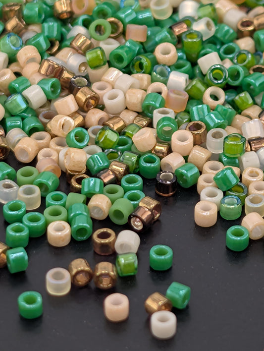 a collection of colorful beads scattered on a dark surface, with various shades of green, beige, and gold beads.