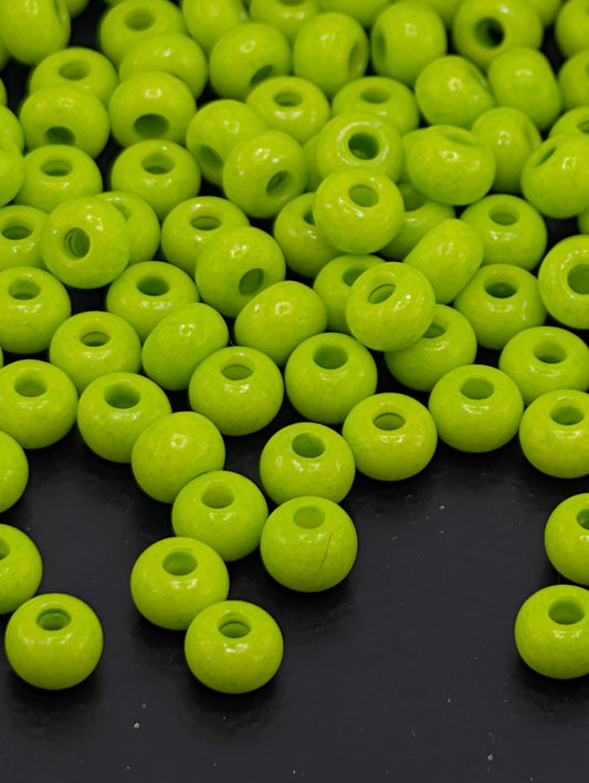 a collection of neon green beads scattered on a dark background.