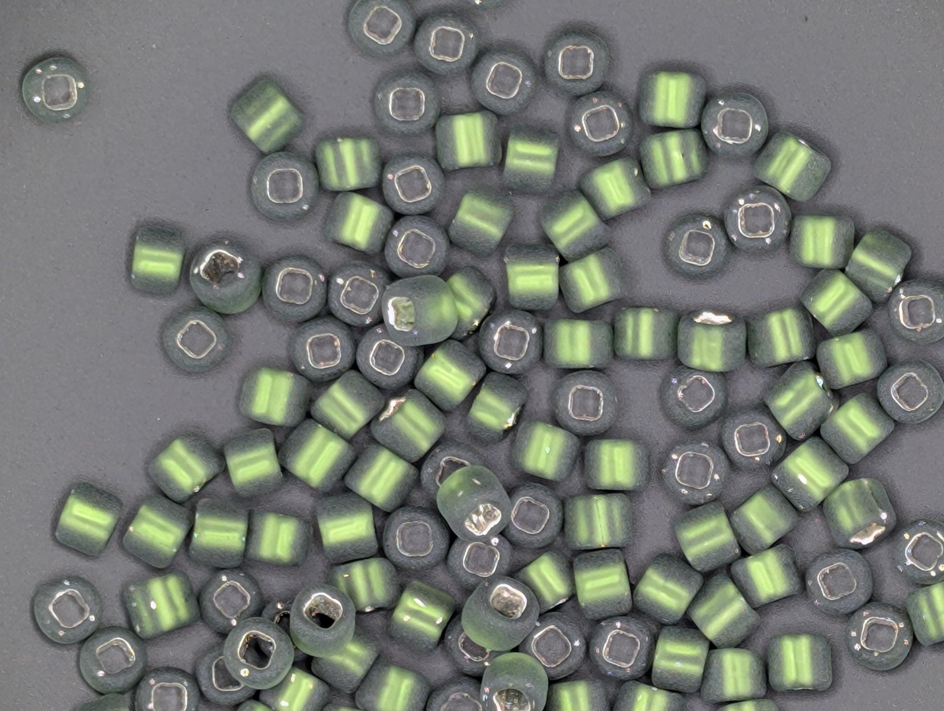 a collection of green and silver beads scattered on a gray background.