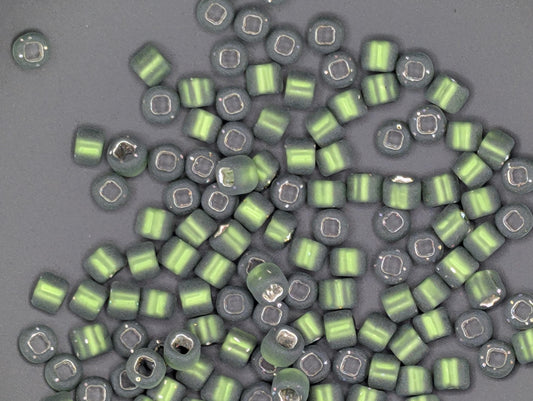 a collection of green and silver beads scattered on a gray background.