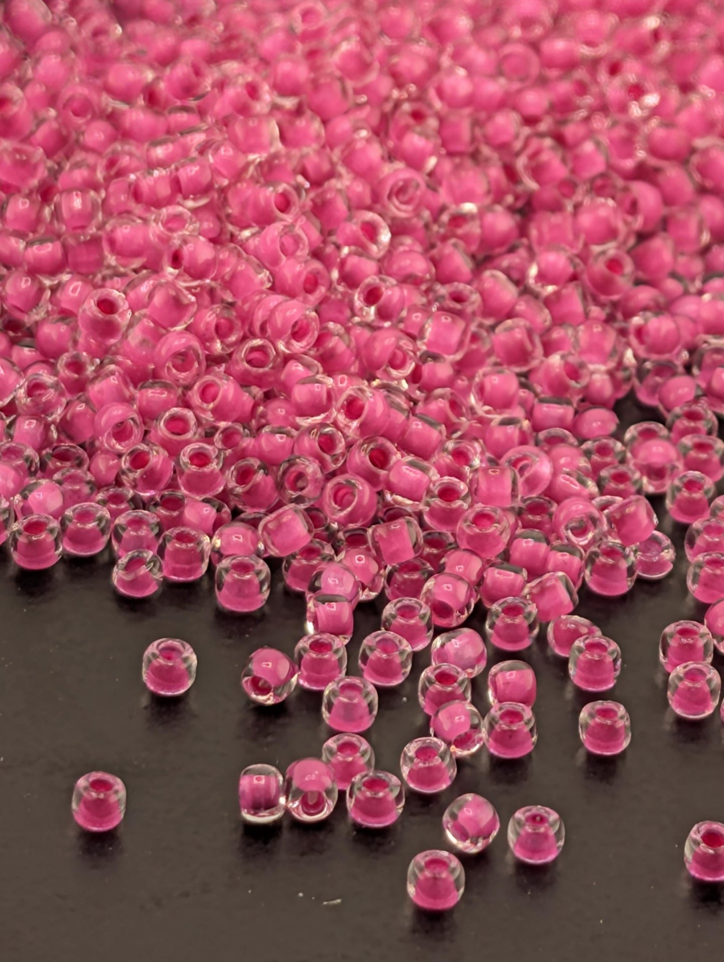 a large pile of clear, pink beads scattered on a dark surface.