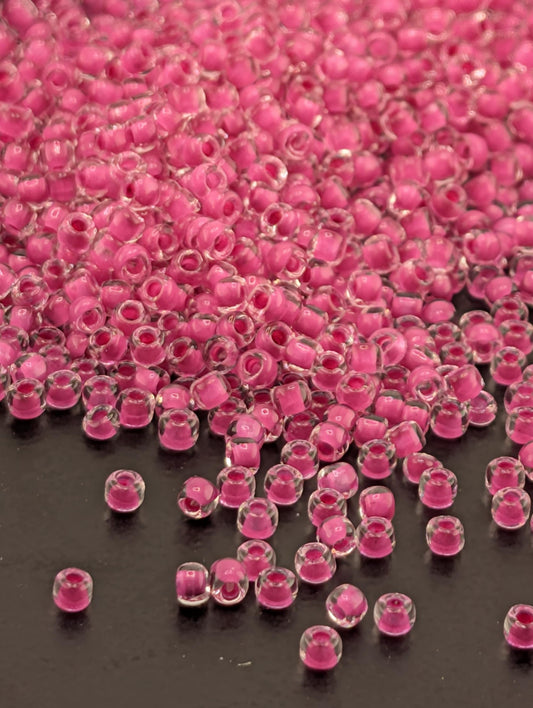 a large pile of clear, pink beads scattered on a dark surface.
