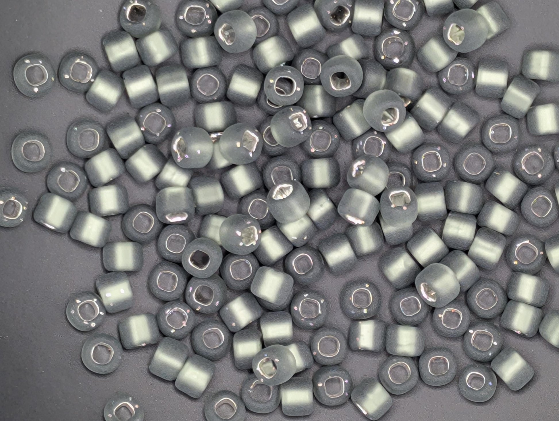 a collection of small, round beads in various shades of gray, scattered across a dark background.