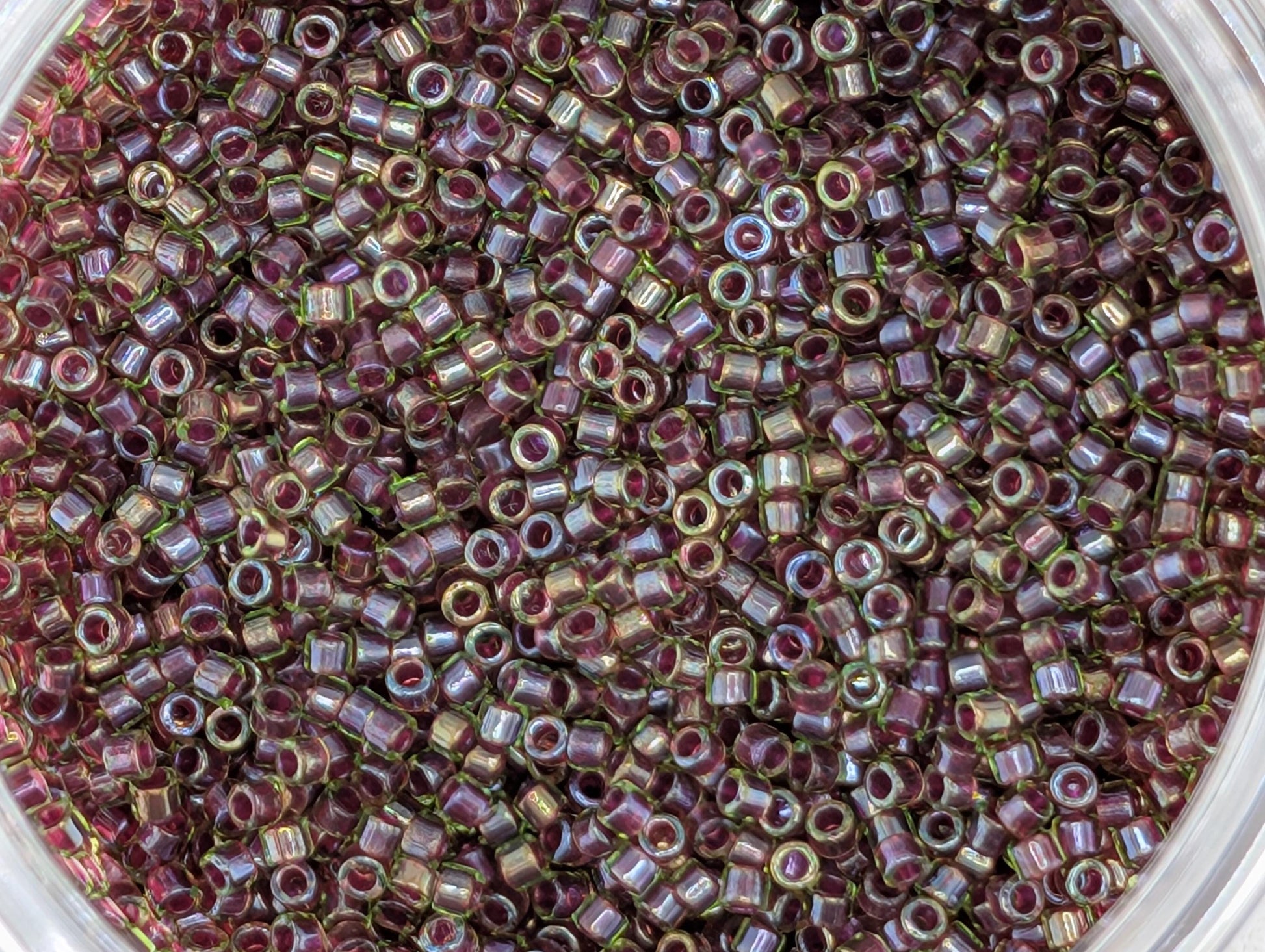 A close-up image of a large pile of small, round beads in various shades of purple and green.