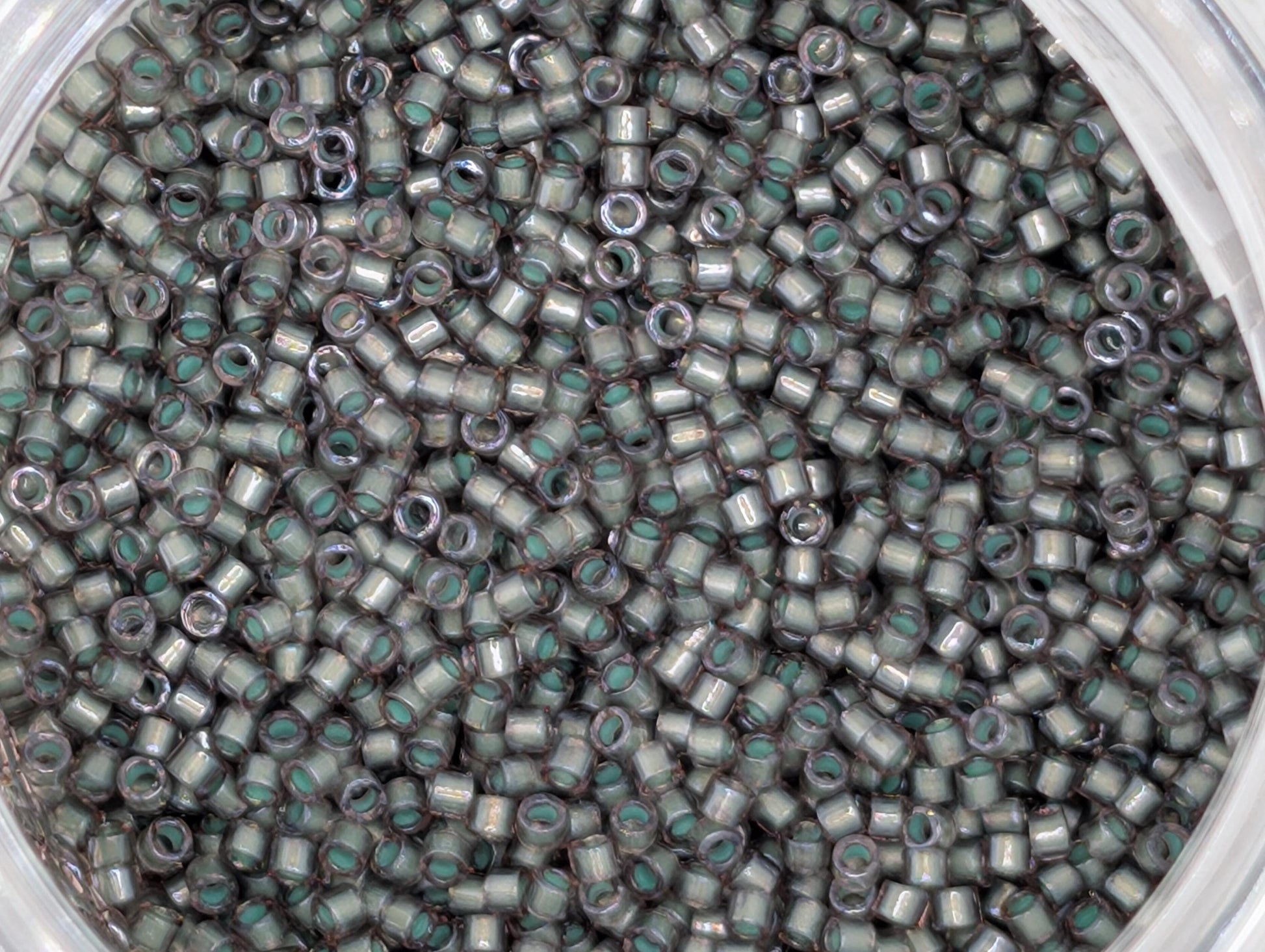 A close-up image of a large pile of small, silver-colored beads or sequins, with a variety of shapes and sizes.