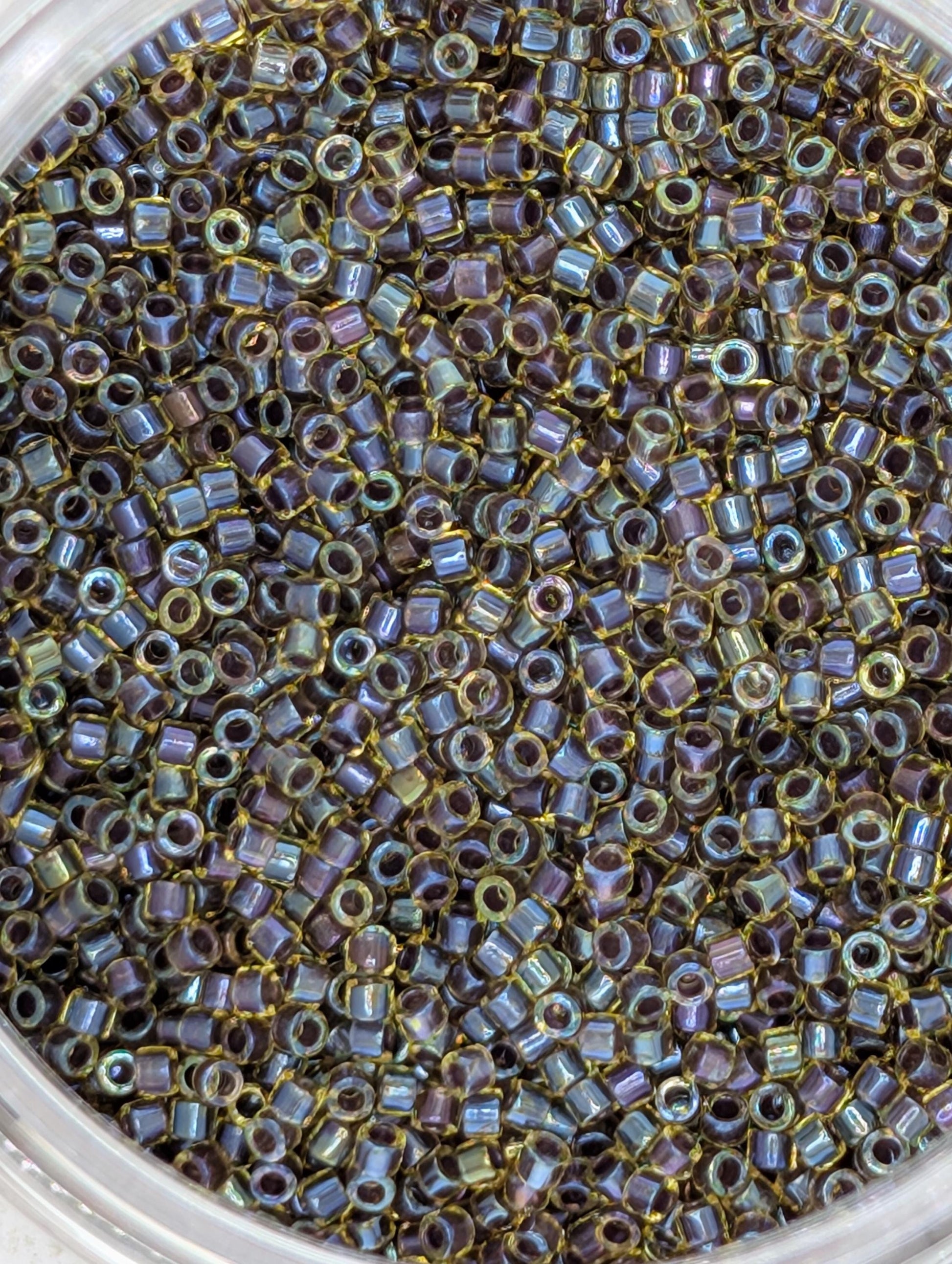 A close-up image of a container filled with numerous small, multicolored beads.