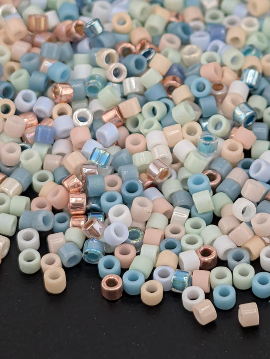 A colorful pile of multicolored beads, including various shades of blue, pink, and white, scattered on a dark surface.