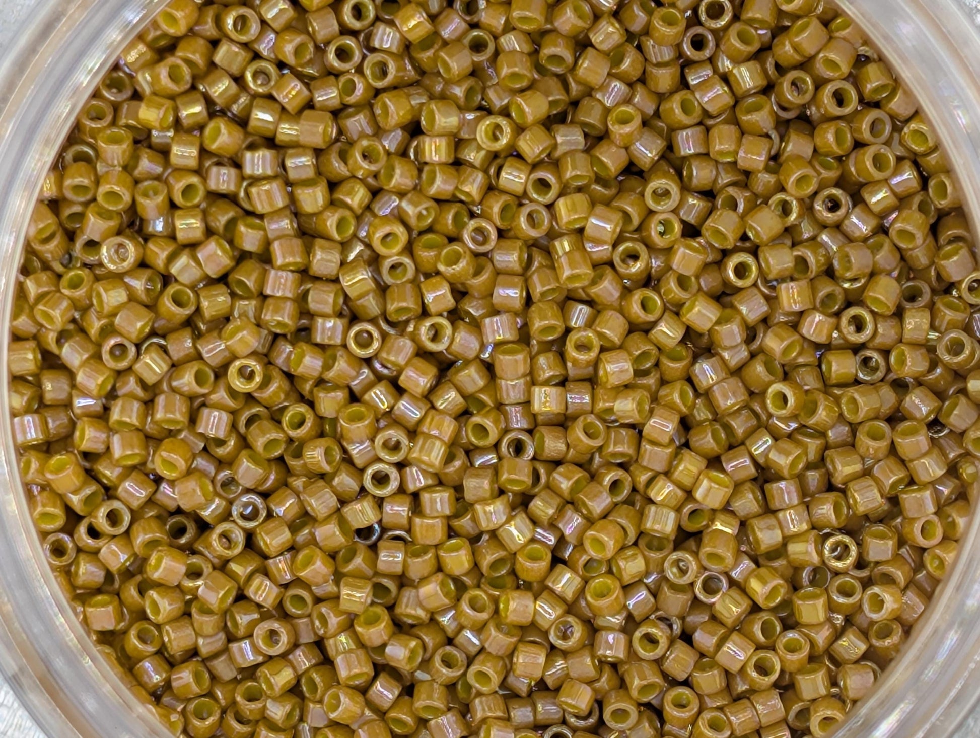 A close-up image of a container filled with small, round, yellow beads or grains.