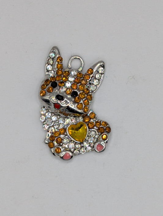 A decorative piece featuring a combination of colorful gemstones and metallic elements, such as a heart-shaped accent and a metallic clasp.