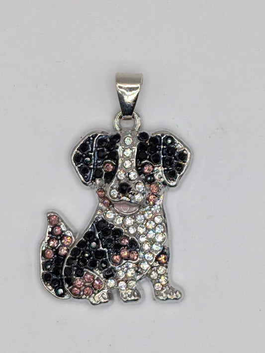 A silver-colored pendant in the shape of a dog, adorned with numerous small rhinestones or crystals.