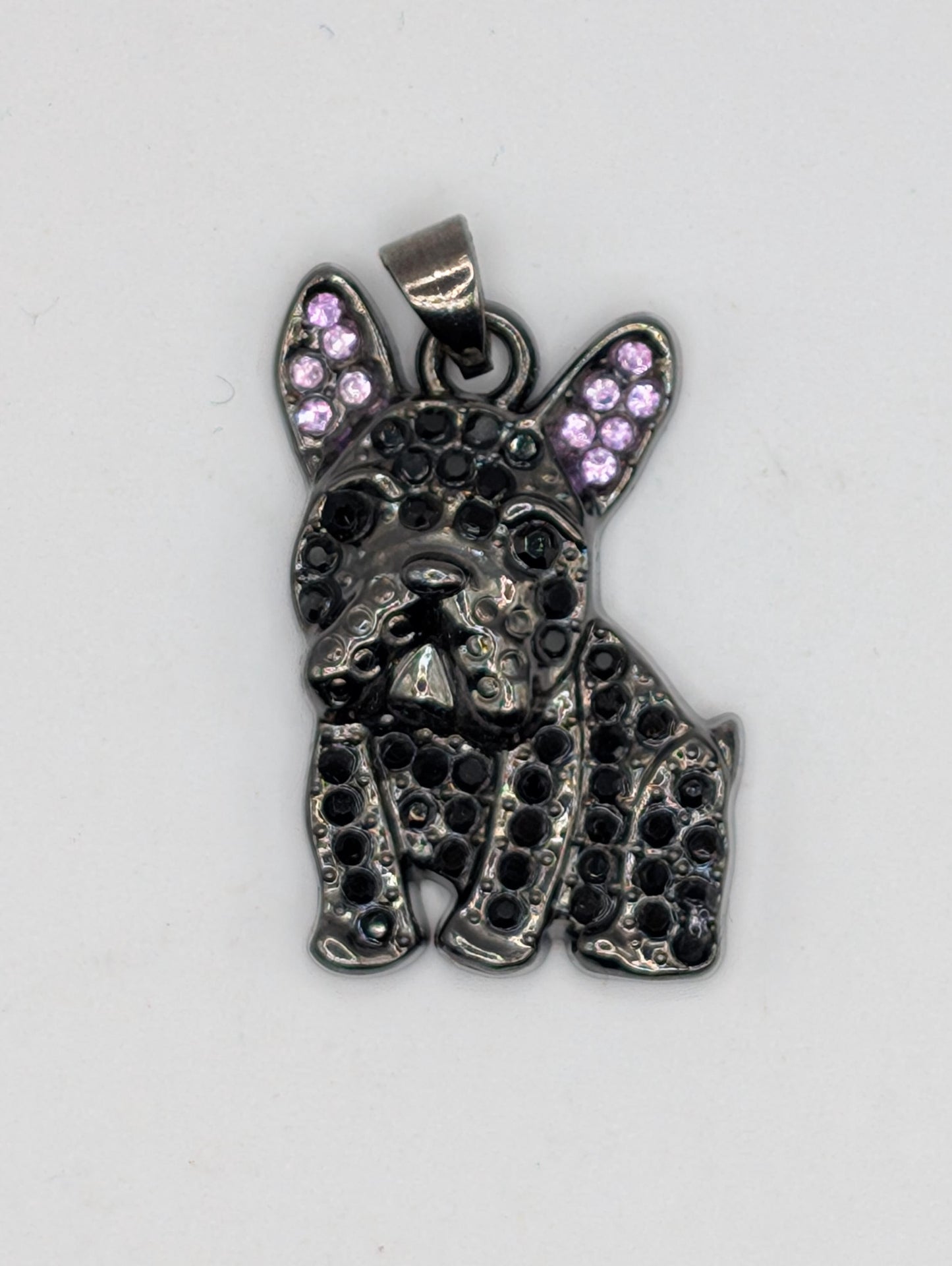 A pendant in the shape of a dog&#39;s head, with a metallic appearance and small purple gemstones or stones embedded in it.