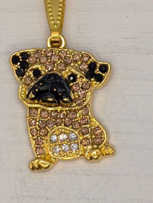 A gold-colored pendant in the shape of a dog, adorned with small diamonds and rhinestones, is the focal point of the image.
