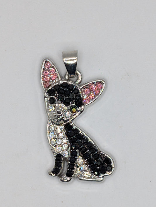 A silver-colored pendant in the shape of a dog, adorned with black and pink rhinestones or crystals.