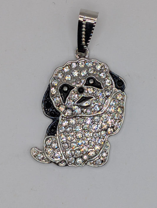 A silver-colored pendant in the shape of a dog, adorned with numerous sparkling rhinestones or crystals.
