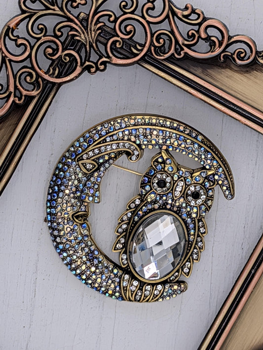 A decorative brooch in the shape of a crescent moon, adorned with numerous sparkling gemstones.