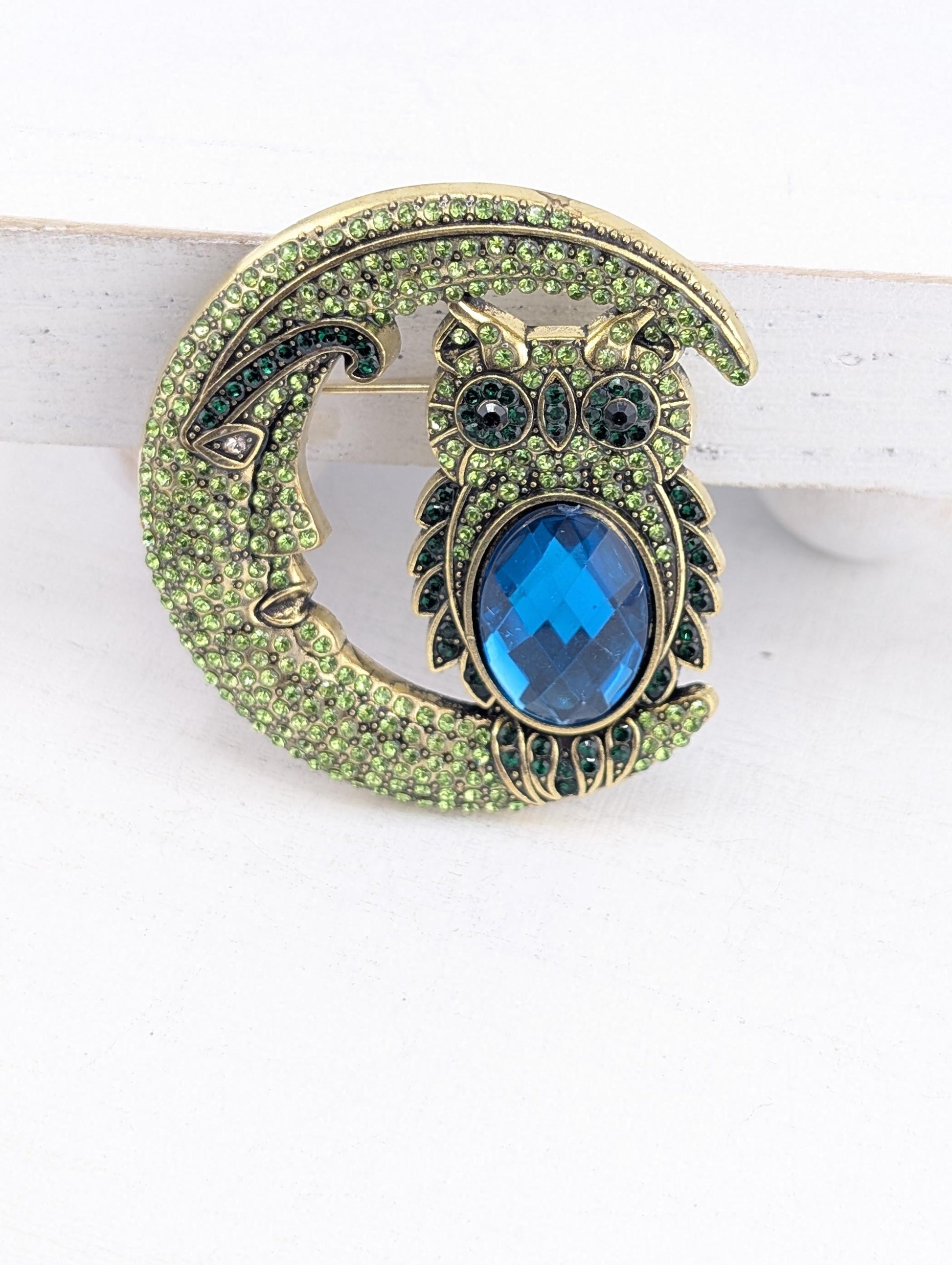 A decorative brooch in the shape of a crescent moon, with a blue gemstone in the center.