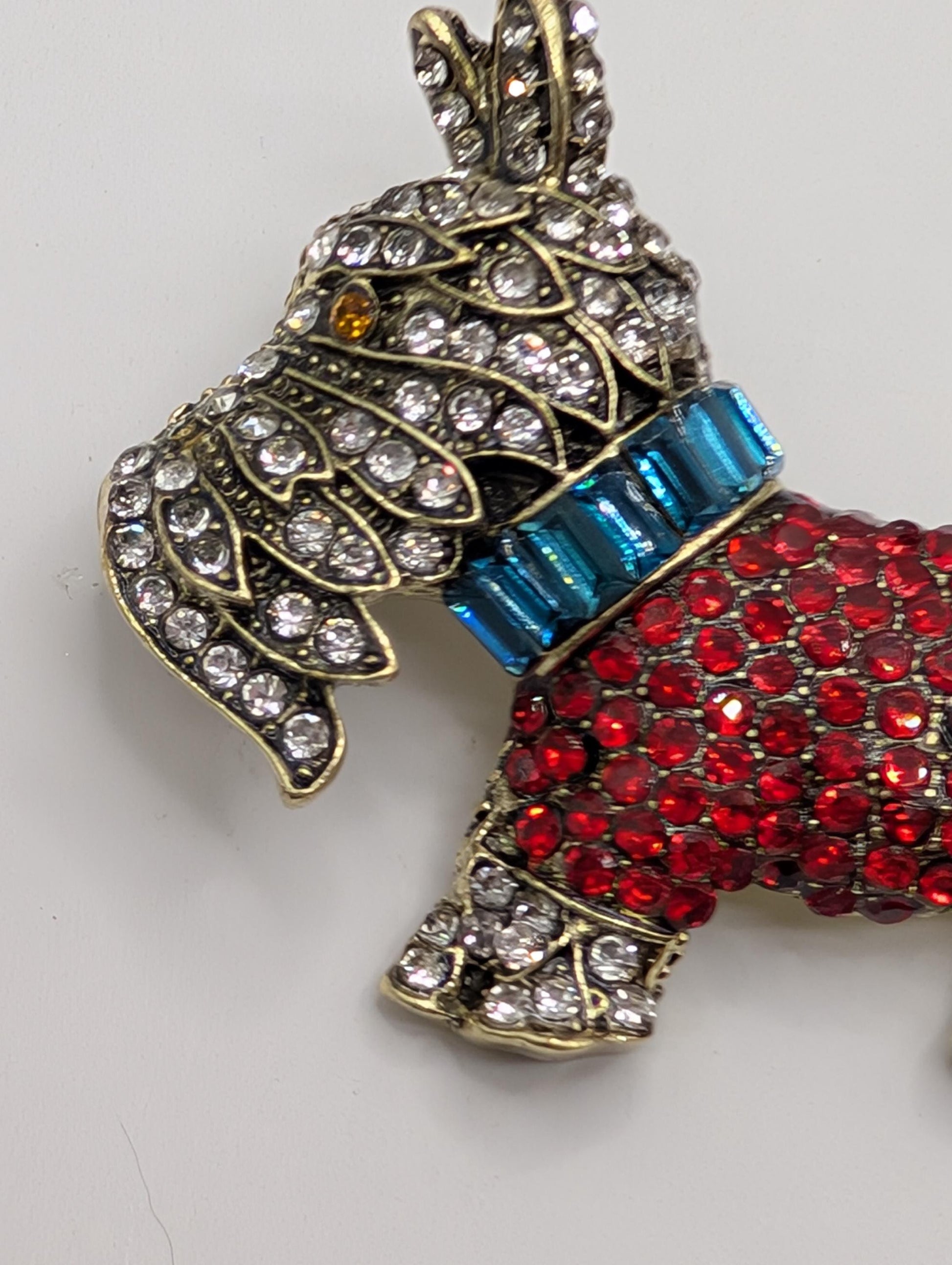 A decorative pendant in the shape of a dog, adorned with sparkling rhinestones and a blue gemstone.