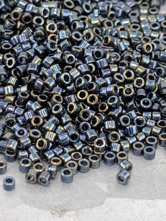 A large pile of small, shiny metal beads in various colors, including black, blue, and gold, scattered on a surface.