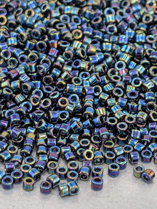 The image is a close-up of a large pile of multicolored beads, including blue, green, and purple beads, scattered across a surface.