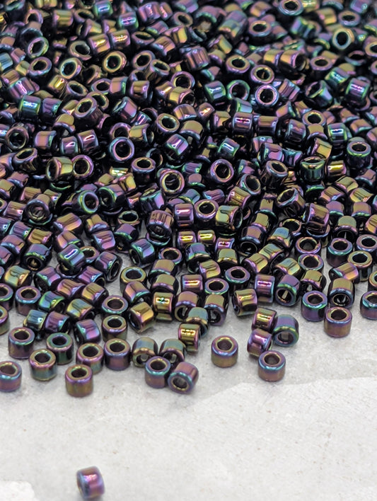 a large pile of multicolored beads, including purple, green, and blue, scattered on a surface.