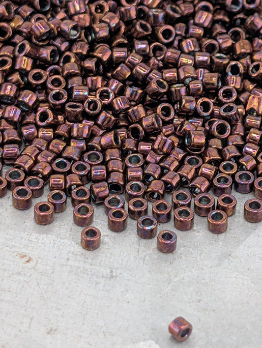 a large pile of small, round beads in various shades of brown, scattered on a white surface.