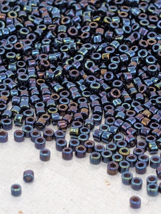 a large pile of multicolored beads, including blue, green, and purple, scattered across a surface.